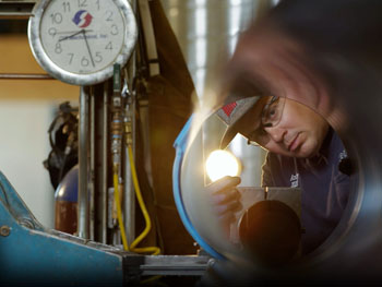 Technician using flashlight reviewing plumbing retrofits