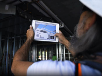 Technician using a tablet on a job site to take pictures for maintenance services